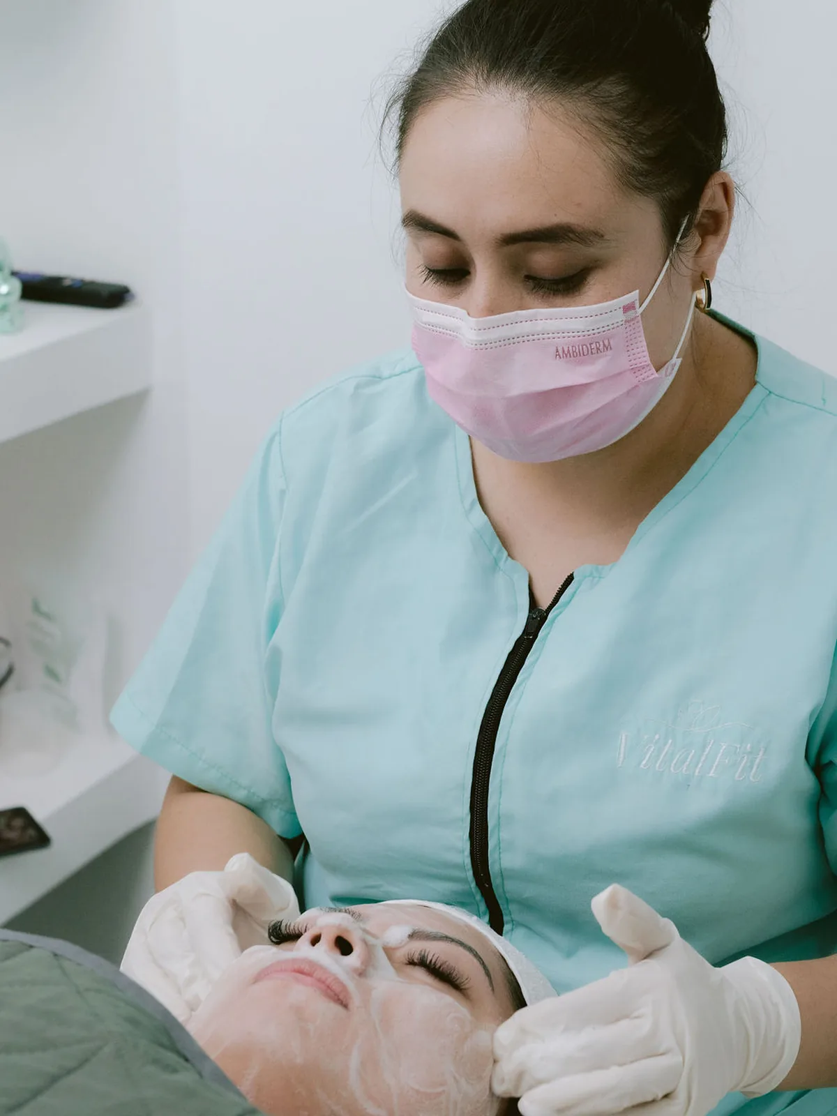 Una terapeuta de VitalFit aplica un tratamiento facial a una paciente.