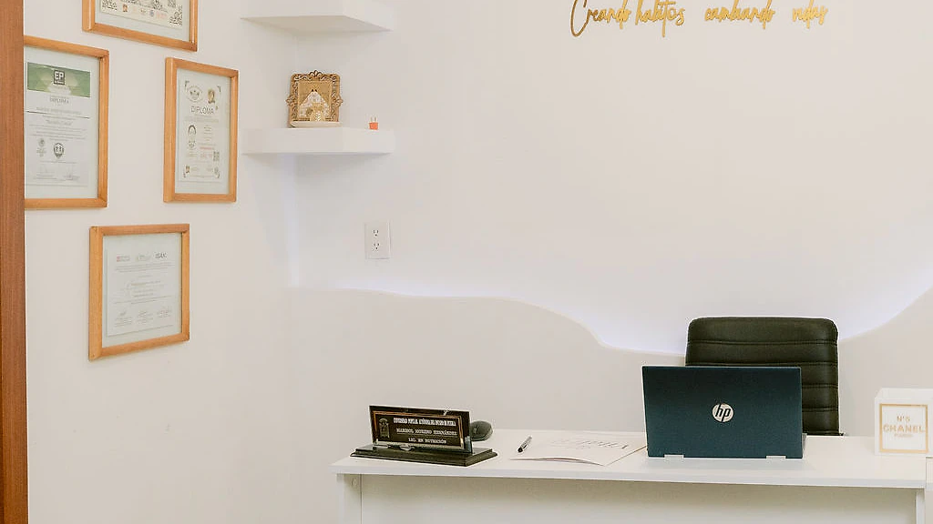 Consultorio de nutrición de VitalFit, con el escritorio y las certificaciones en la pared